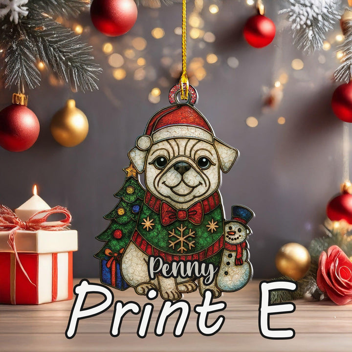 A Christmas ornament in the shape of a dog wearing a Santa hat and scarf, with a snowman and a gift box nearby. The ornament is hanging from a string, and there are red and gold ornaments and a lit candle in the background.